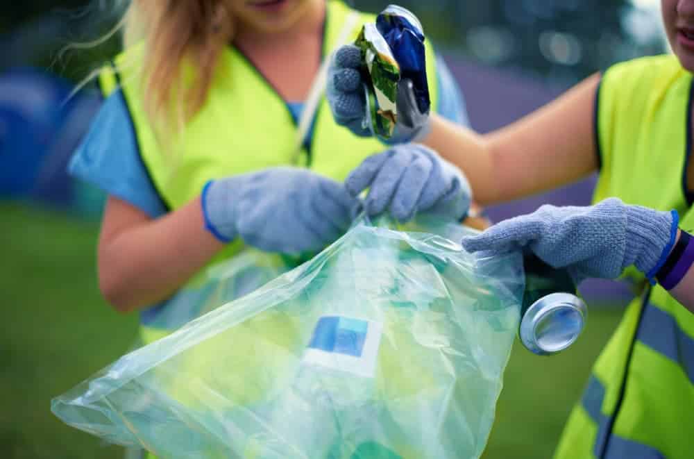 Dvoje-mladih-zena-prikupljaju-smece-u-plasticne-vrece-na-otvorenom-prostoru.